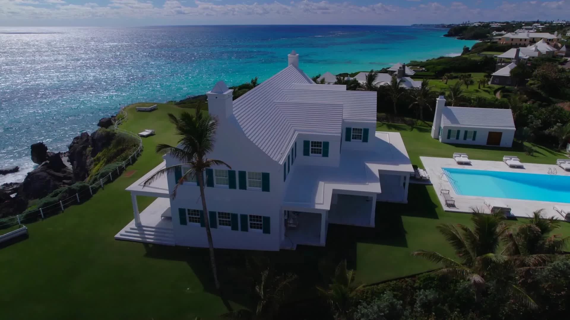 The Bermuda estate at dusk, the pool lit against the water