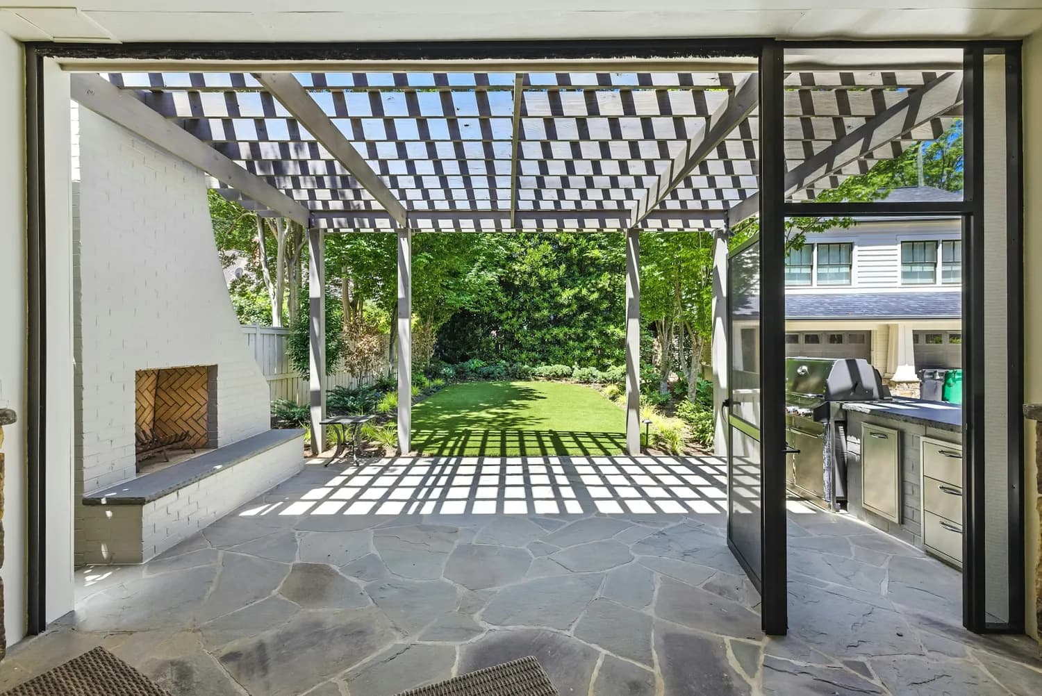 A luxury home's covered terrace and outdoor kitchen, settled and ready for the season