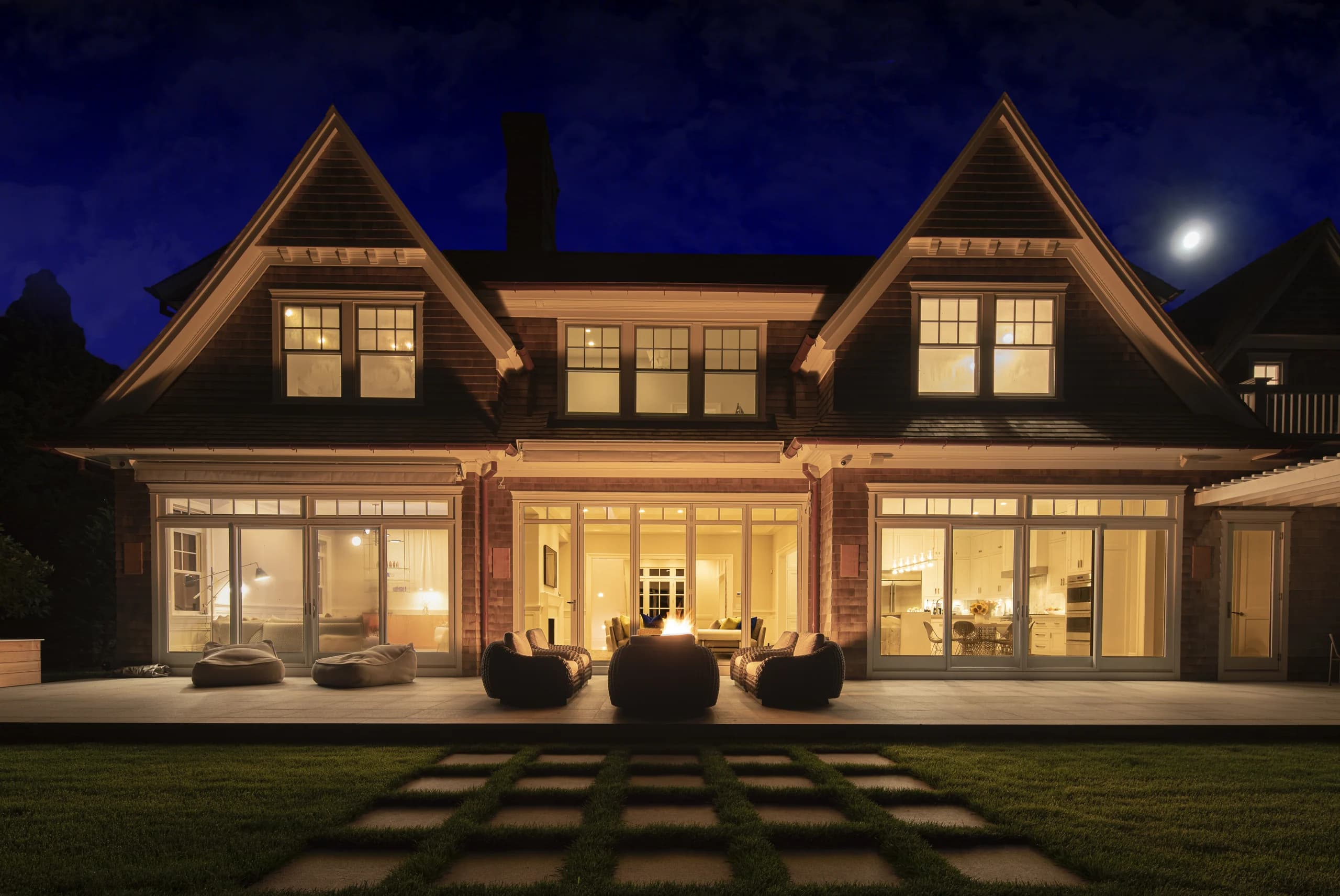 The Hamptons wellness estate at dusk, each room lit a different colour