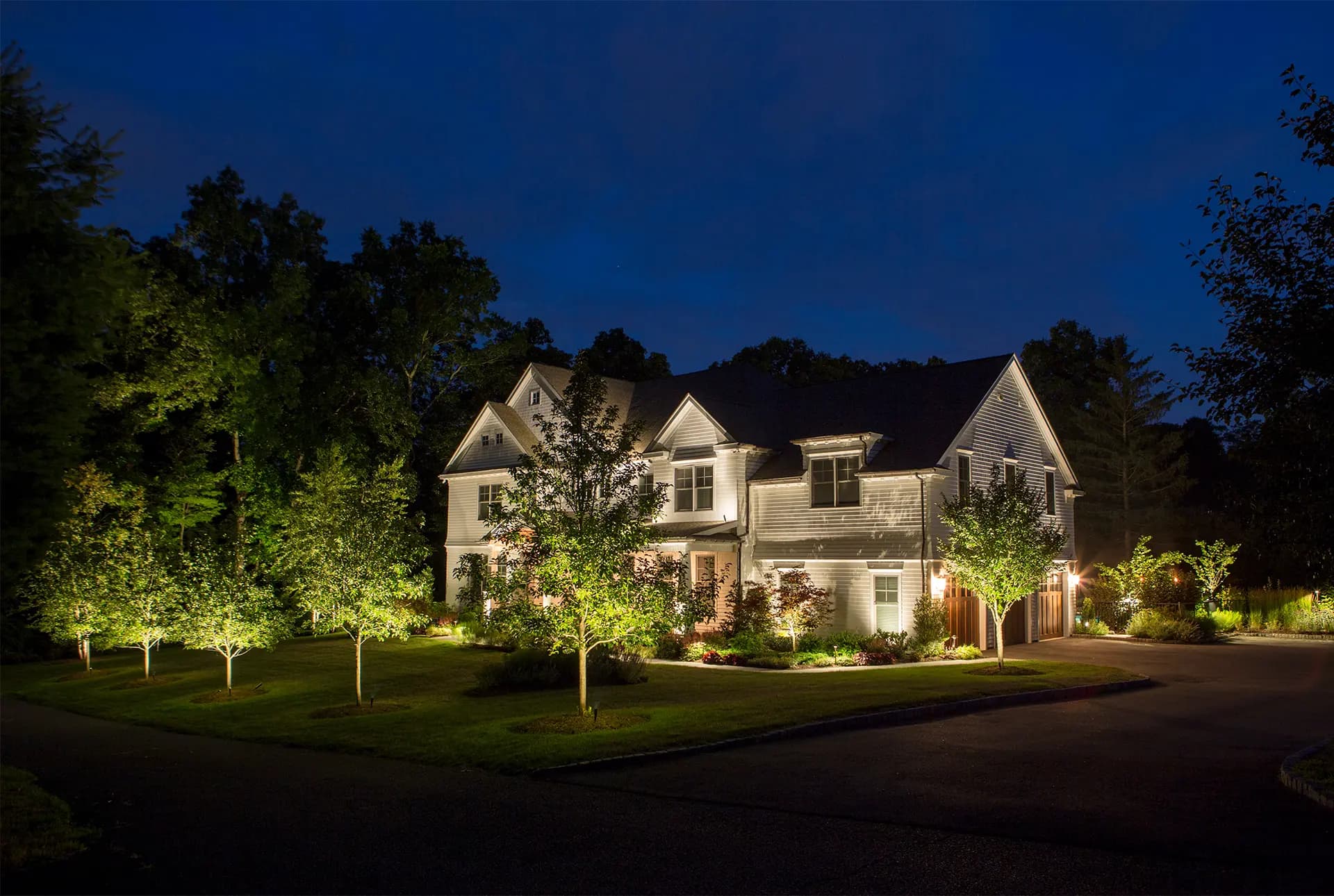 A garden at dusk, layered with warm Coastal Source landscape lighting