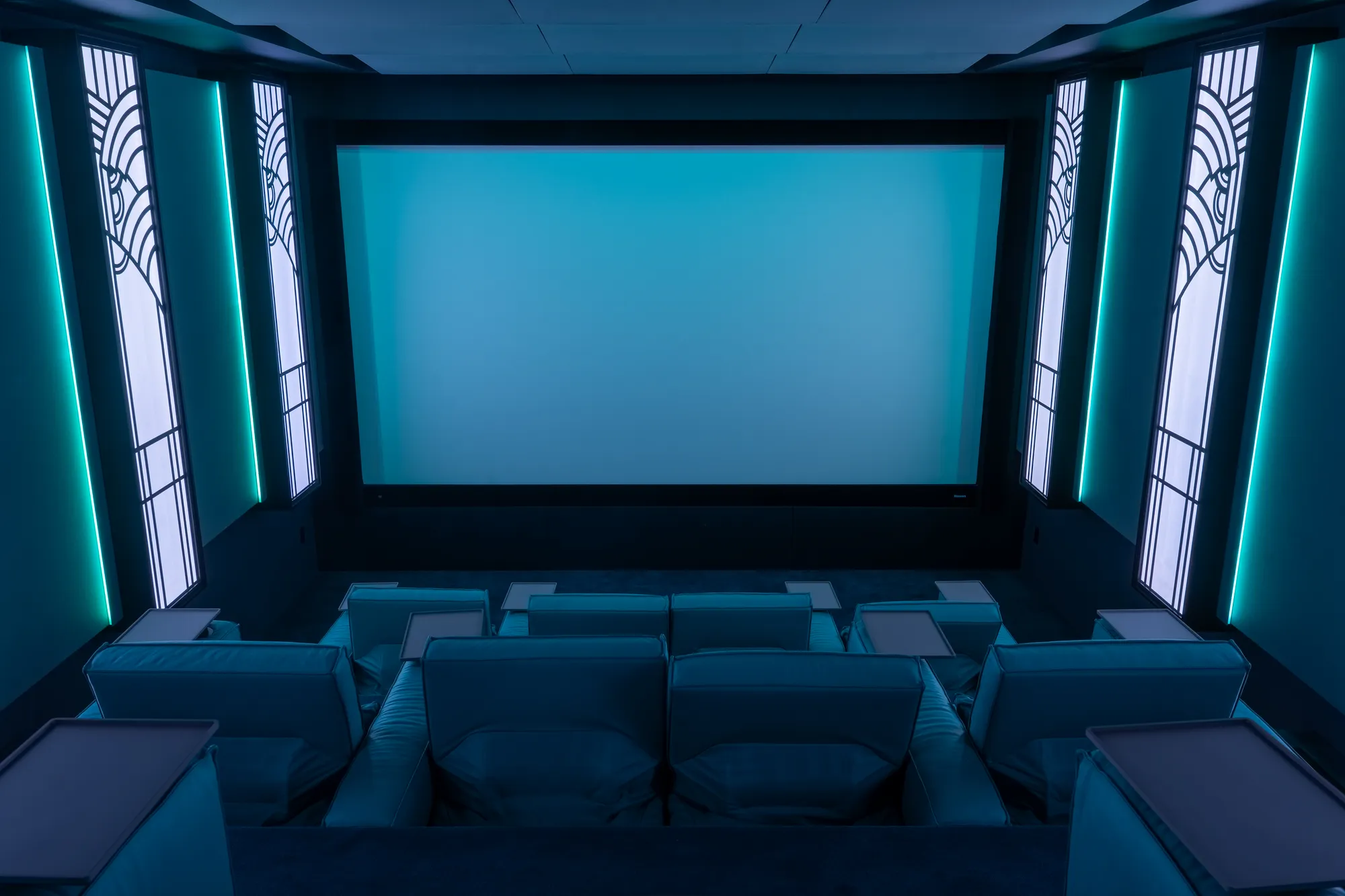 The finished cinema in teal light, with Cineak leather seating and Art Deco panels