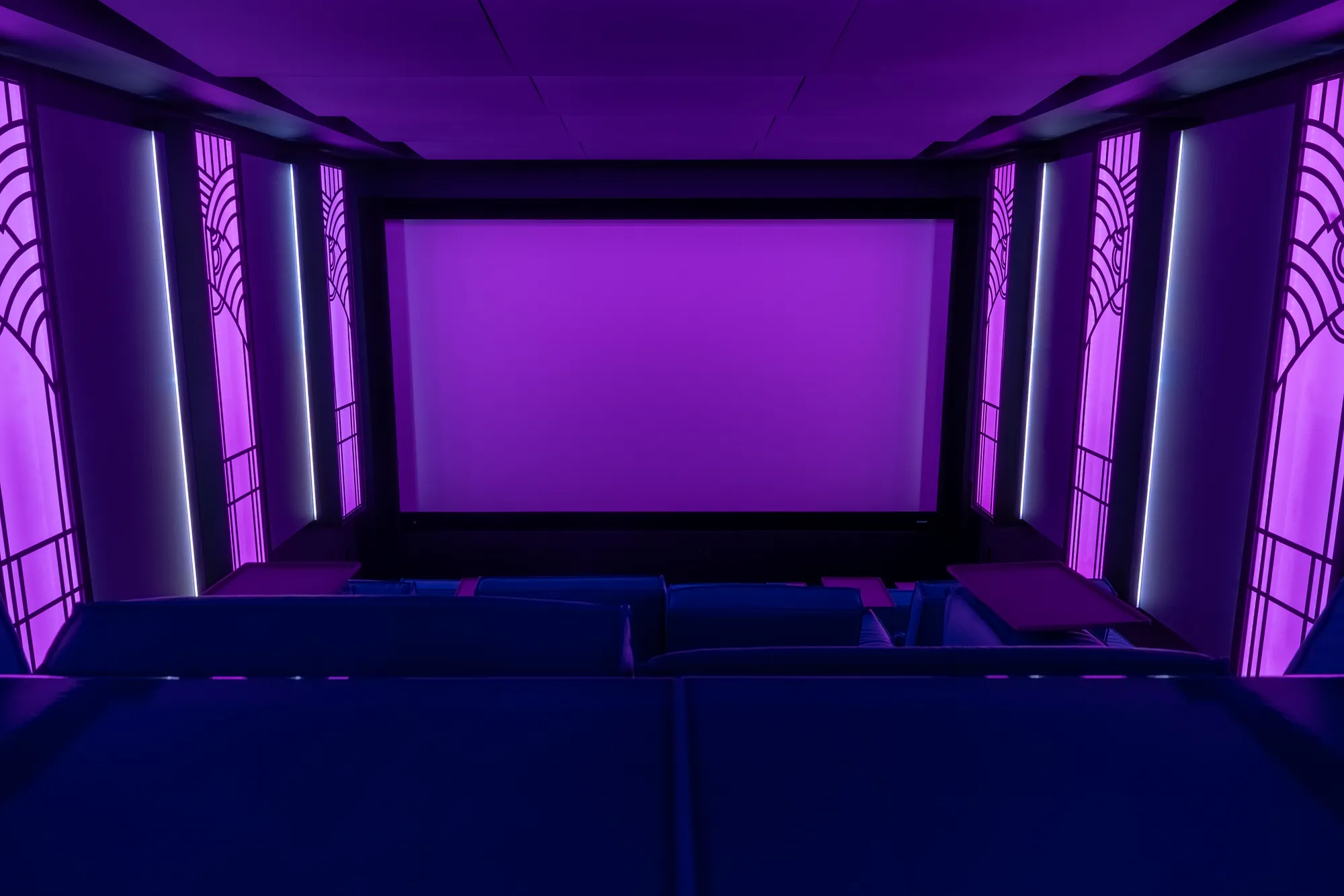 The cinema in deep magenta light, the screen lit and ready