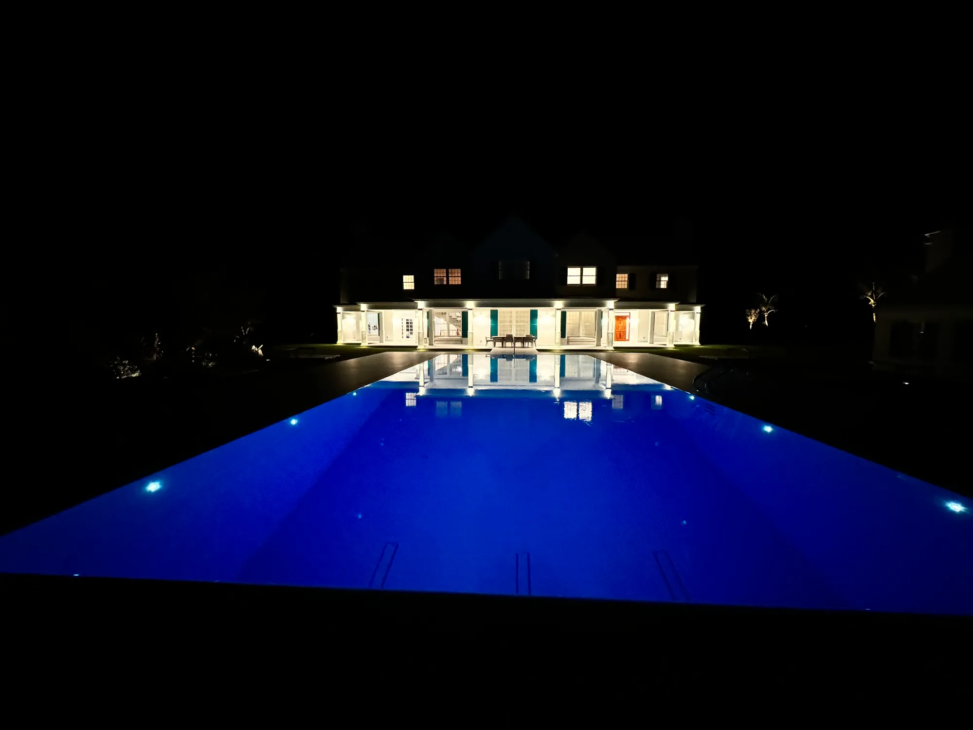 The pool glowing at night, the estate quiet and lit