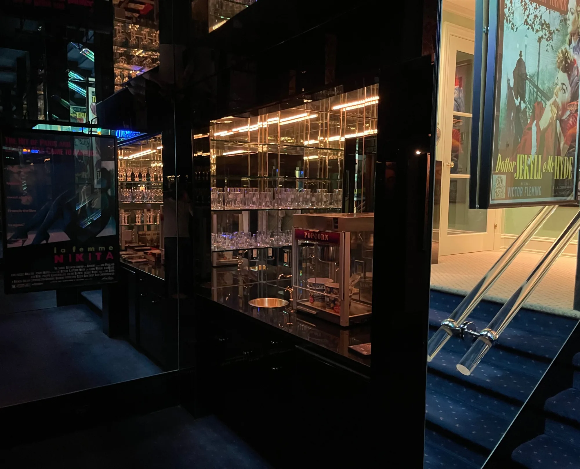 A mirrored bar with glassware and a popcorn machine outside the cinema
