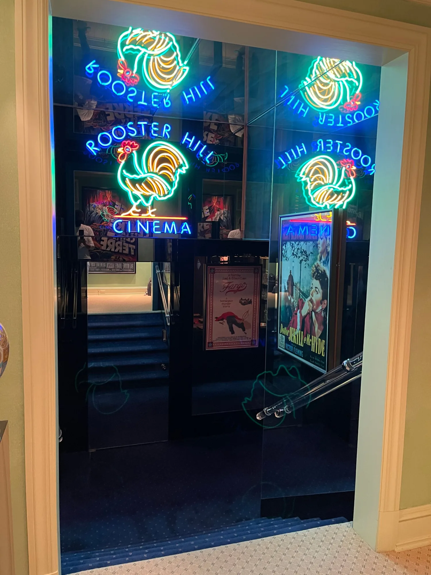 The Rooster Hill Cinema neon marquee and mirrored walls above the stairs