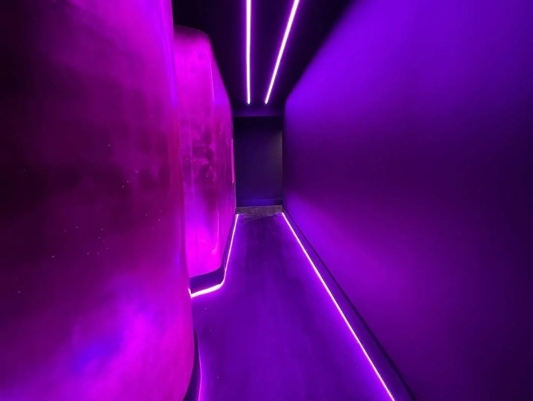 A hall washed in magenta and violet, LED lines along the floor and ceiling