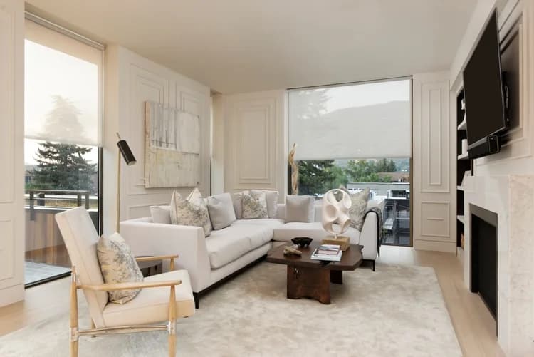 A refined living room where Savant shades filter the daylight across a wall of windows