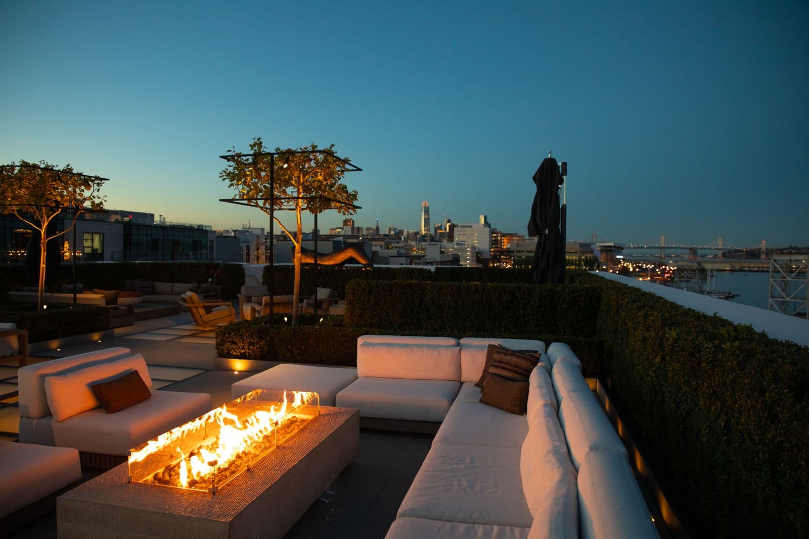 A luxury terrace with a firepit at dusk, scored by concealed outdoor audio