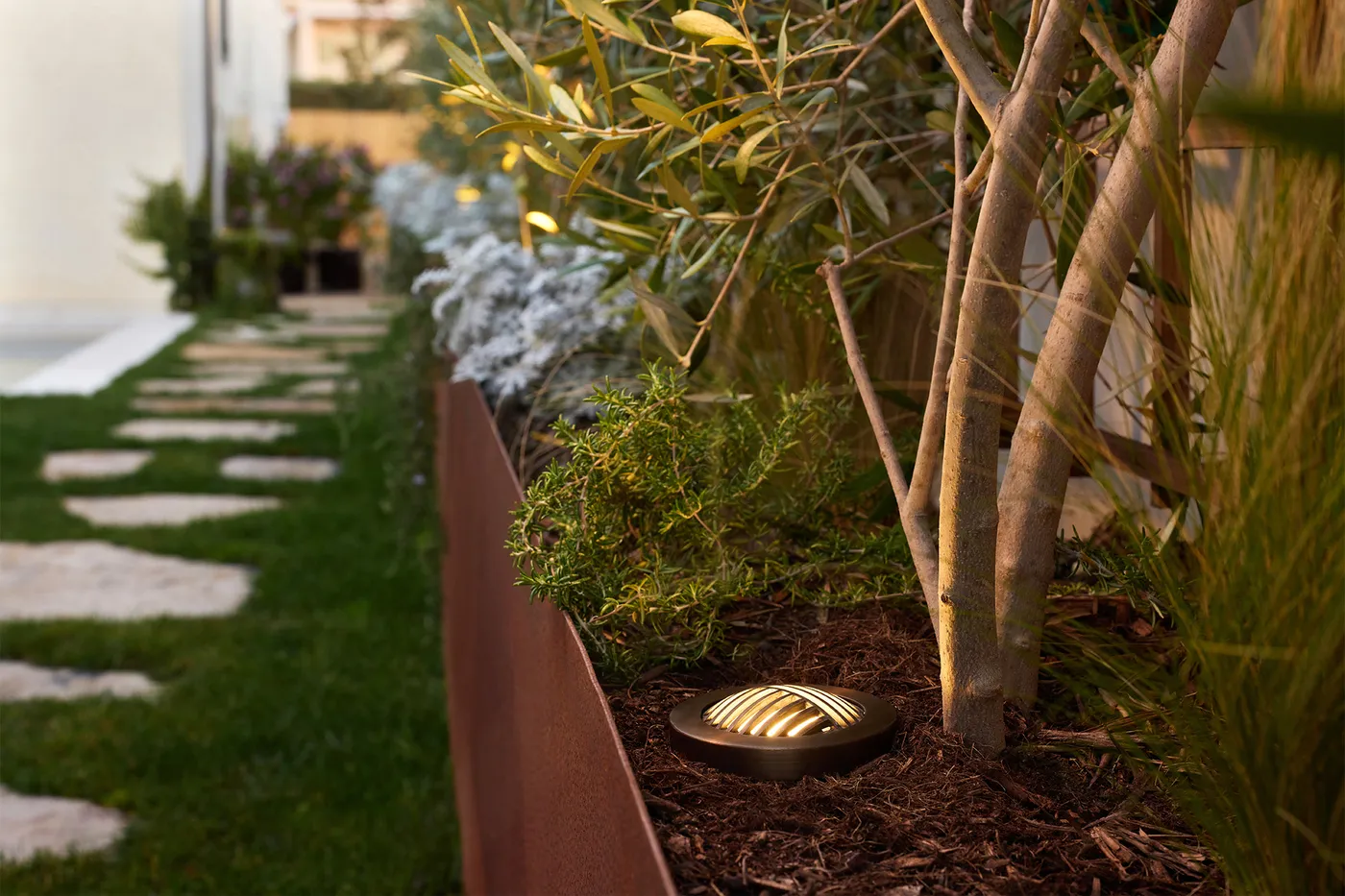 Flush in-grade well lights running along a stone path through planting